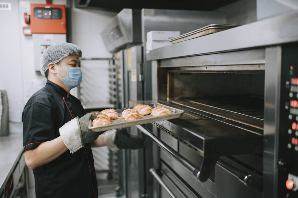 commercial kitchen bakery owner baking bread taking out from oven