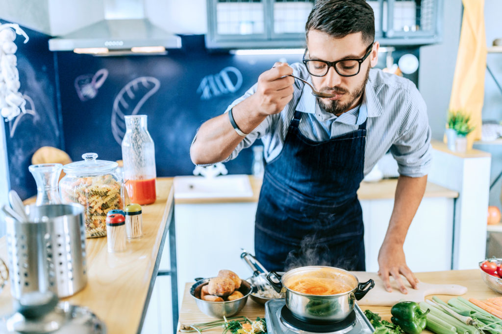 Photo of chef tasting delicious lunch he is preparing in the kitchen