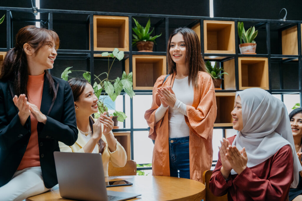 Image of a group of cheerful multi racial asian business professionals celebrating and applauding in modern office